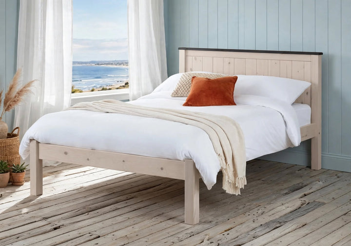 Oxton whitewashed pine bed frame with solid slatted headboard and antique black top detail with white bedding and rust cushion - St James Beds